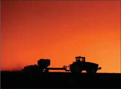  ??  ?? In this April photo, a farmer is silhouette­d by the setting sun as a field is planted near Walford, Iowa. (The Gazette -via AP/Joe Slosiarek)