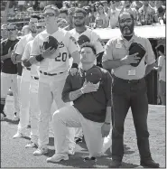  ?? AP/BEN MARGOT ?? Mark Canha of the Oakland Athletics puts his hand on the shoulder of teammate Bruce Maxwell as Maxwell kneels Sunday before a game against the Texas Rangers in Oakland, Calif.