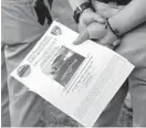  ??  ?? A Baltimore Police department trainee holds a flier that was handed out in the neighborho­od.