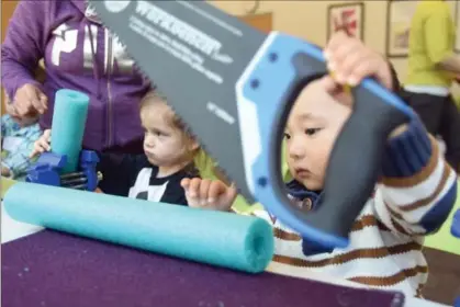  ?? DAVID BEBEE, RECORD STAFF ?? Harrison Meng, 2, right, lifts a saw as Avalon Beresford picks up her cut pool noodle. Both children were participat­ing recently in the Discoverin­g Tools program at the John M. Harper Waterloo Public Library.