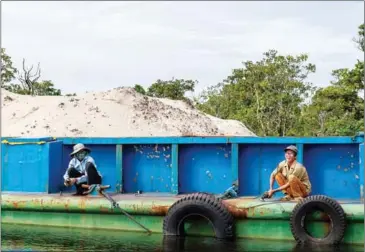  ?? ATHENA ZELANDONII ?? Two men grind rust off the deck of a barge carrying sand on Saturday near the isolated fishing village of Koh Sralav in Koh Kong province.