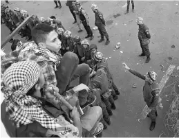  ?? PETR DAVID JOSEK/ THE ASSOCIATED PRESS ?? Protesters sit on concrete blocks as Egyptian soldiers stand guard in front of the presidenti­al palace in Cairo on Sunday.