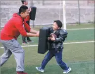  ??  ?? A coach shows a boy how to use a punch pad.