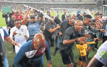  ?? /Samuel Shivambu/BackpagePi­x ?? Mayhem: Former Kaizer Chiefs coach Steve Komphela (in black jacket and jeans) runs for cover with match officials, players and police after his team was knocked out of the Nedbank Cup by Free State Stars on Saturday night. He quit soon afterwards.