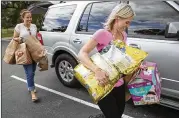  ?? RICARDO B. BRAZZIELL / AMERICAN-STATESMAN ?? Krista Harmon (left) and Natalie Kifer carry items Monday at the Circle C Community Center in South Austin that have been donated to victims of Hurricane Harvey.