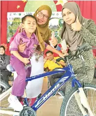  ??  ?? MUHAMMAD Raiyyan Nazryl murid pra sekolah menerima basikal daripada Dg Sarifah (dua kanan) pada Majlis Penghargaa­n Jom Hadir Ke Sekolah 2017.