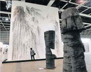  ??  ?? The wooden sculptures “Les Spectateur­s (Man and Woman)”, created by Chinese artist Wang Keping, and the
painting “Beholding the Mountain with Awe” created by Xu Longsen are displayed at Art Basel Hong Kong.