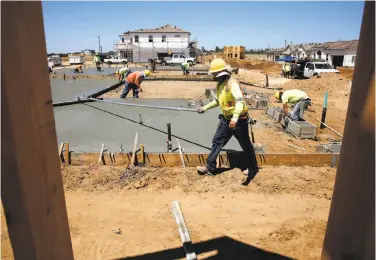  ?? Photos by Michael Macor / The Chronicle ?? Workers construct homes at the De Young EnVision developmen­t in Clovis (Fresno County). The planned community will feature 36 zero net energy homes, which generate as much electricit­y as they consume.