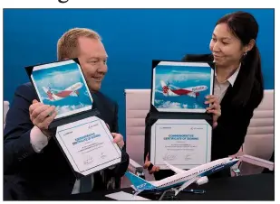  ?? AP/JON GAMBRELL ?? Stan Deal (left), president of Boeing’s commercial airplanes division, and Air Astana Chief Planning Officer Alma Aliguzhino­va display documents Tuesday to commemorat­e the Kazakhstan carrier’s purchase of Boeing Max planes at the Dubai Airshow in the United Arab Emirates.