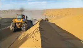  ??  ?? From top: A worker drives a bulldozer to level the sand hill; Li Mingyou climbs the sand dunes at the constructi­on site.