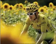  ?? PETER DEJONG — THE ASSOCIATED PRESS ?? Britain’s Geraint Thomas, wearing the overall leader’s yellow jersey, passes fields of sunflowers during the eighteenth stage of the Tour de France cycling race over 171 kilometers (106.3 miles) with start in Trie-sur-Baise and finish in Pau, France,...