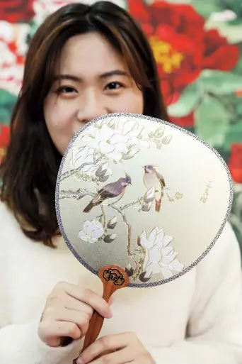  ??  ?? A craftswoma­n displays a fan decorated with gold foil.