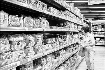  ??  ?? A customer walking past different brands of instant noodles for sale in a supermarke­t in Hong Kong.