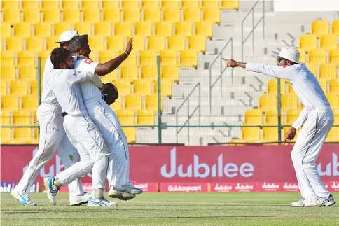  ?? — AFP photo ?? Sri Lanka’s Rangana Herath (R) celebrates with his team after victory on the fifth day of the first Test cricket match between Sri Lanka and Pakistan at Sheikh Zayed Stadium in Abu Dhabi on October 2, 2017.