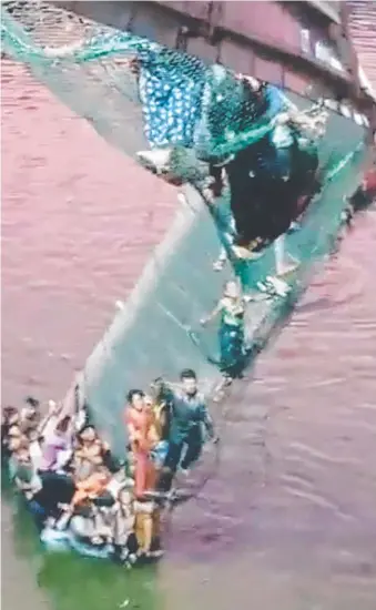  ?? ?? Survivors cling to the remains of the bridge after it collapsed in western India. Pic: Twitter