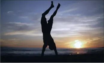  ??  ?? WAKE UP: A man does a handstand at sunrise. Let a little Vitamin D into your life and food and feel the health benefits.