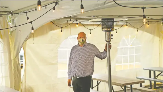  ?? JEAN LEVAC ?? Peter West, of Bowman's Bar and Grill on Carling Avenue, set up heaters and a tent over his parking lot patio earlier this week to prepare for the cold weather.