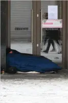  ??  ?? A homeless person endures the snow