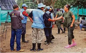  ?? AP ?? A United Nations observer shakes hands with a rebel from the FARC group, before a meeting in La Carmelita, in Colombia’s southweste­rn state of Putumayo on Wednesday.