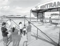  ??  ?? Disappoint­ed shop owners stand at the locked gate of theSwapSho­p& Thunderbir­d Drive-InTheater in Fort Lauderdale onTuesday.