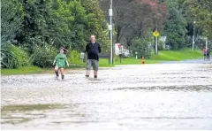  ?? AFP ?? Residents wade through a flooded street after torrential rain at the suburb of Langholm in Auckland, New Zealand, yesterday.