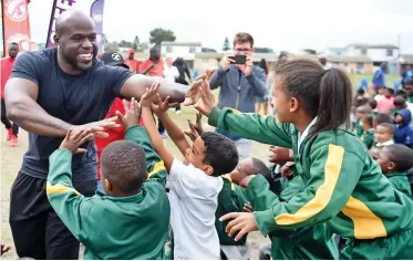  ?? PICTURE: PHANDO JIKELO/AFRICAN NEWS AGENCY/ANA ?? CENTRE OF ATTENTION: WWE superstar Apollo Crews gives Cedar Primary School pupils a high-five during his visit to the Bonteheuwe­l school with Mandy Rose.