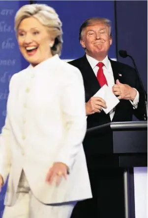  ??  ?? LAS VEGAS: Hillary Clinton walks off stage as Donald Trump grimaces
