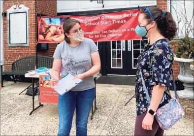  ?? Grace Duffield / Hearst Connecticu­t Media ?? Francesca DeRosa was signing a petition given to her by Amy Zinser on Sunday in front of the New Canaan Playhouse that will prompt a referendum that, if passed, will reverse a decision on school start times.