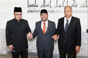  ??  ?? Let peace reign: Dr Mujahid (centre) is all smiles after the meeting between Dr Asri and Dr Ramasamy in Putrajaya ended on a friendly note.