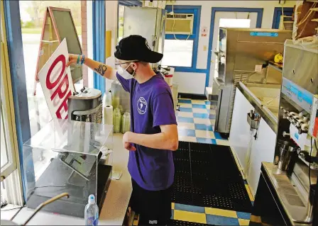  ?? SEAN D. ELLIOT/THE DAY ?? Employee Ryan Jones shifts the sign from Closed to Open on Friday at Tony D’s Craft Creamery in Niantic. The business has been busy since it opened for the season April 25.