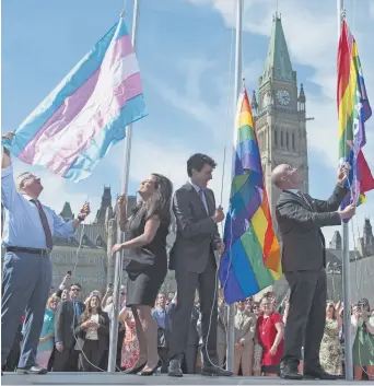  ??  ?? Le drapeau transgenre (à gauche) a été hissé aux côtés de drapeaux de la fierté gaie sur la Colline parlementa­ire à Ottawa, jeudi. – La Presse canadienne: Adrian Wyld