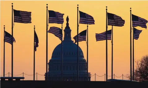  ?? JON ELSWICK/ASSOCIATED PRESS ?? American flags blow in the wind around the Washington Monument with the U.S. Capitol in the background at sunrise on Jan. 20, 2020.