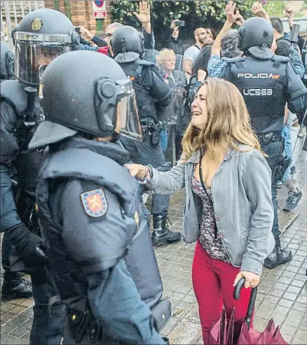 ?? QUIQUE GARCÍA / EFE ?? Una joven llora ante un antidistur­bios tras una carga policial a la puerta de un colegio electoral