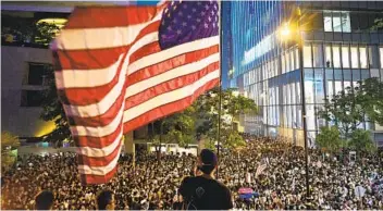  ?? ANTHONY WALLACE AFP VIA GETTY IMAGES ?? A man waves a U.S. national flag as protesters attend a rally in Hong Kong on Oct. 14, 2019.