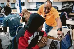  ?? Brett Coomer / Staff photograph­er ?? Science teacher Dominick Virola helps his students on their assignment­s for summer school last week at Kashmere High, which is set to meet academic standards.