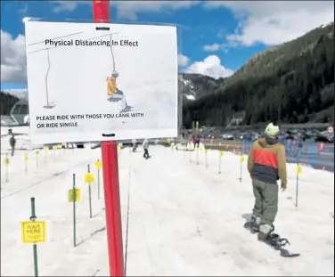  ?? Andy Cross / The Denver Post ?? Physical distancing massages at the entrance to the Black Mountain Express lift during the reopening of the Arapahoe Basin ski area May 27.