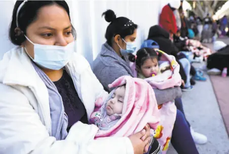  ?? Mario Tama / Getty Images ?? People from El Salvador and Honduras who are seeking asylum in the U.S. wait Friday at the border crossing in Tijuana.