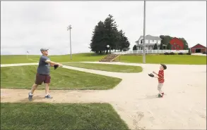  ?? Charlie Neibergall / Associated Press ?? Jeremiah Bronson, of Ames, Iowa, plays catch with his son Ben, right, on the field at the “Field of Dreams” movie site in Dyersville, Iowa.