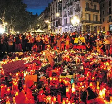  ?? EMILIO MORENATTI / THE ASSOCIATED PRESS ?? Mourners gather at a memorial on Barcelona’s Las Ramblas promenade to the victims of Thursday’s terror attacks that killed 14 people. Spanish police on Friday killed five people during a later attack 100 kilometres to the south.