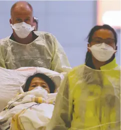  ?? Shanon Vanraes / Reuters files ?? Winnipeg paramedics dressed in protective clothing and wearing masks guide a stretcher carrying an ill woman who was on a flight from Vancouver to a waiting ambulance at the airport in Winnipeg last month.