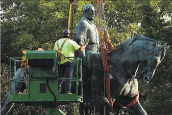  ?? Win McNamee / Getty Images ?? Workers in Charlottes­ville place straps around a statue of Confederat­e Gen. Robert E. Lee so it could be lifted onto a truck for removal to storage from the city’s Market Street Park.