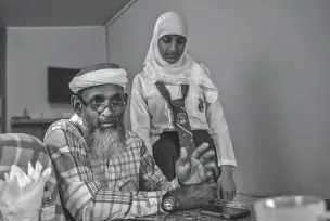  ??  ?? Umar Abdullah, an Islamic activist, is shown at home Feb. 7 with his daughter in Port of Spain, Trinidad and Tobago. Abdullah, who once encouraged would-be fighters, now says Muslims must work with the U.S. to ‘change the narrative.’