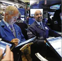  ?? RICHARD DREW / ASSOCIATED PRESS ?? Traders work on the floor of the New York Stock Exchange on Monday, when the Dow, S&P 500 and Nasdaq all achieved record highs amid broad investor optimism.