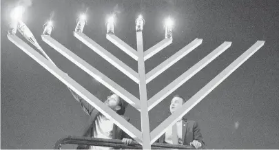  ?? MATTHEW COLE/THE CAPITAL GAZETTE ?? Rabbi Nochum Light lights the menorah while Annapolis City Mayor Michael Pantelides looks on during the annual Menorah Car Parade and Lighting held at Susan Campbell Park last year. This year’s lighting is Dec. 25 at City Dock from 5:45 to 6:30 p.m.