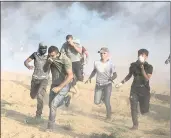  ?? KHALIL HAMRA — THE ASSOCIATED PRESS ?? Palestinia­n protesters run for cover from tear gas fired by Israeli troops during a protest at the Gaza Strip’s border.