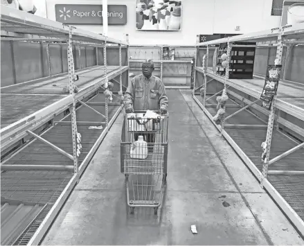  ?? MIKE DE SISTI / MILWAUKEE JOURNAL SENTINEL ?? A shopper moves his cart in an aisle that’s normally stocked with toilet paper and other paper products at Walmart on West Brown Deer Road in Brown Deer on March 16, 2020.