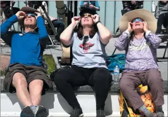 ?? DETROIT NEWS PHOTO ?? From left, Peter Najar of Bingham Farms, Katie Morrison of Taylor, and Susan Najar of Bingham Farms view Monday’s solar eclipse from the ERB family garden at Cranbrook Institute for Science.