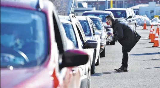  ?? Sean McKeag ?? The Associated Press Pharmacist Mike Ruane of Scranton, Pa., talks Friday to patients at a drive-thru vaccinatio­n clinic at Scranton High School.