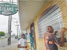  ?? Matthew Hinton, The Associated Press ?? Frank Turner, left, and Keith Brooks work to protect the windows of the Crescent City Steaks restaurant Friday in New Orleans before landfall of Tropical Storm Barry from the Gulf of Mexico.