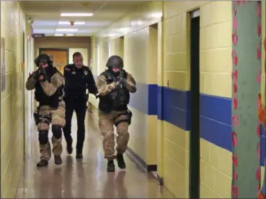  ?? OMAR RICARDO AQUIJE ?? Members of the Washington County Sheriff’s Office and the Hudson Falls Police Department use unloaded guns to take part in an emergency drill as they walk through a corridor inside the Hudson Falls Primary School in Hudson Falls, N.Y.